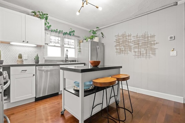 kitchen with dark countertops, light wood finished floors, appliances with stainless steel finishes, and a kitchen breakfast bar