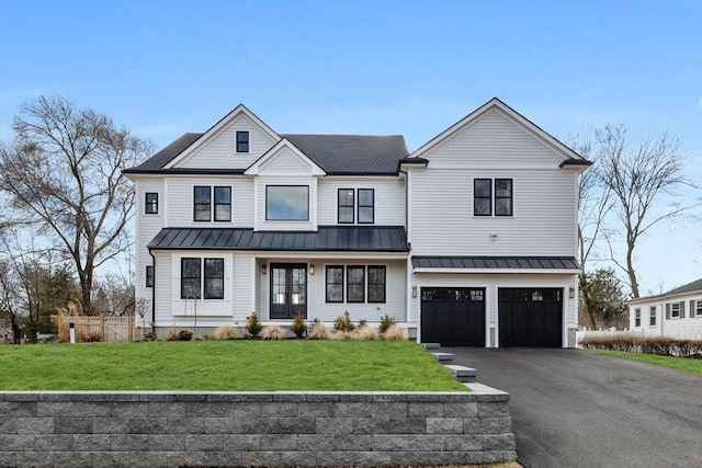 view of front facade with an attached garage, a front yard, metal roof, driveway, and a standing seam roof