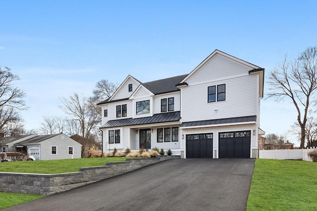 view of front of home featuring a standing seam roof, a front lawn, fence, and aphalt driveway