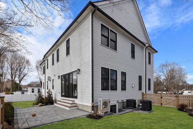 back of property with a patio area, a lawn, entry steps, and central AC