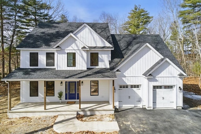 modern farmhouse style home featuring board and batten siding, roof with shingles, covered porch, a garage, and driveway