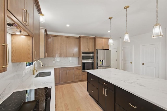 kitchen featuring light stone countertops, decorative backsplash, hanging light fixtures, stainless steel appliances, and a sink