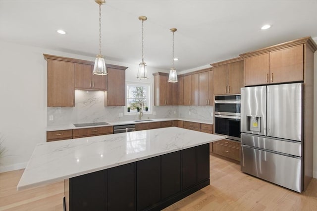 kitchen with a sink, stainless steel appliances, backsplash, and light wood finished floors