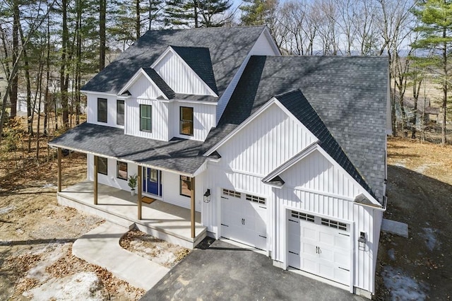 modern farmhouse with a porch, driveway, board and batten siding, and roof with shingles