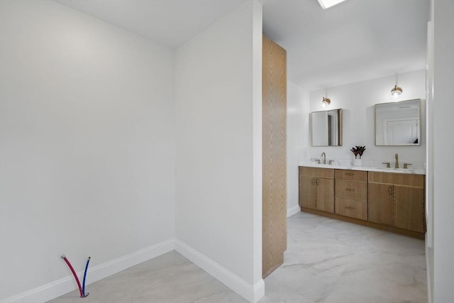 full bathroom featuring double vanity, baseboards, and a sink