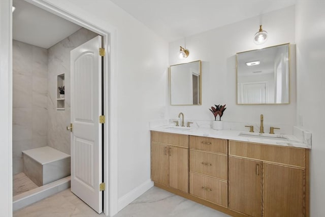 bathroom with double vanity, marble finish floor, a tile shower, and a sink