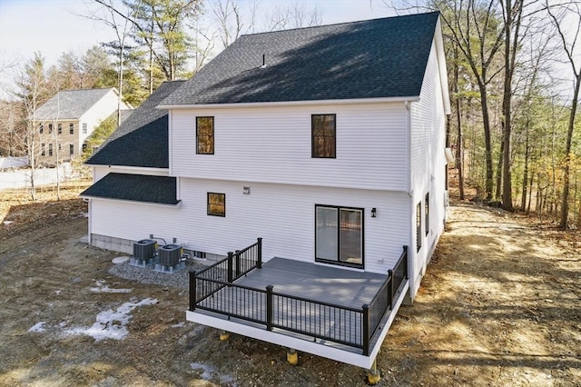 rear view of house with central AC unit, a wooden deck, and roof with shingles