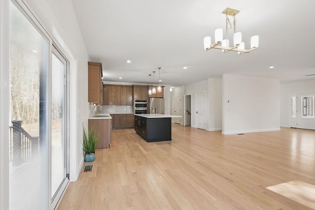 kitchen with visible vents, a kitchen island, light countertops, appliances with stainless steel finishes, and light wood-type flooring