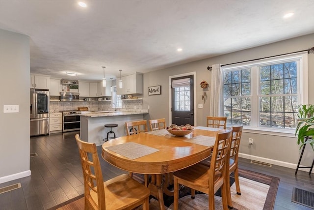 dining area with visible vents, dark wood-type flooring, and baseboards