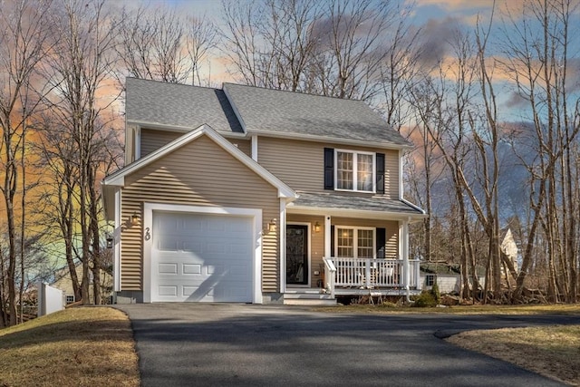 traditional-style house featuring an attached garage, a porch, driveway, and a shingled roof