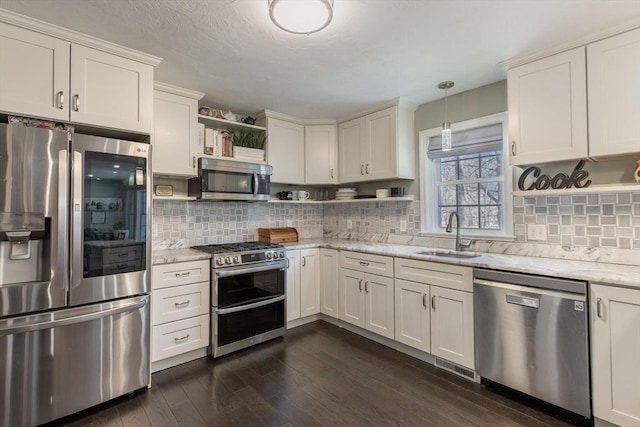 kitchen featuring dark wood finished floors, open shelves, a sink, decorative backsplash, and appliances with stainless steel finishes