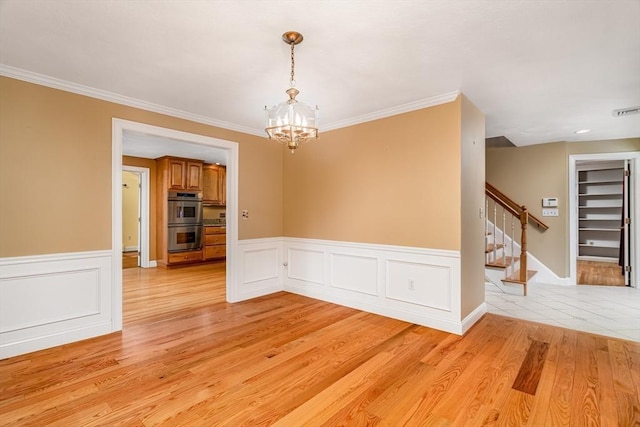 unfurnished room with a chandelier, light hardwood / wood-style floors, and ornamental molding