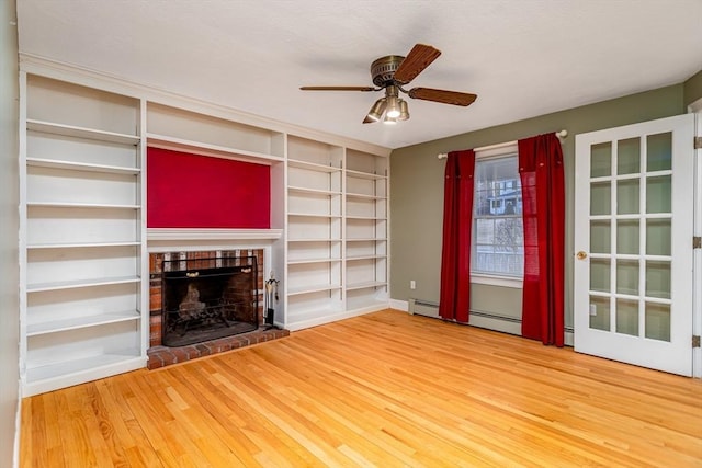 unfurnished living room with hardwood / wood-style flooring, ceiling fan, built in features, and a brick fireplace