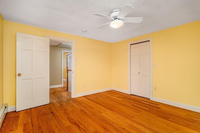 unfurnished bedroom with ceiling fan, light hardwood / wood-style floors, and a baseboard radiator