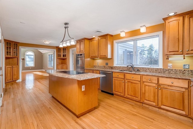 kitchen with pendant lighting, a kitchen island, light hardwood / wood-style floors, and appliances with stainless steel finishes