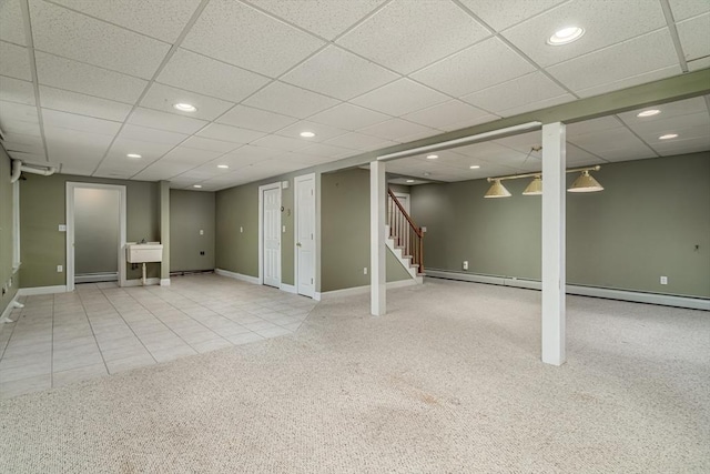 basement with tile patterned flooring, a paneled ceiling, and baseboard heating