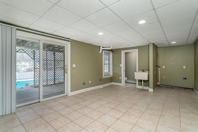 empty room with a paneled ceiling, sink, and a baseboard heating unit