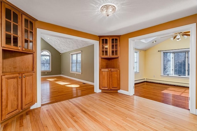 interior space with plenty of natural light, light hardwood / wood-style floors, ceiling fan, and vaulted ceiling