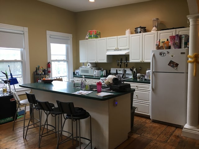 kitchen featuring white appliances, dark hardwood / wood-style floors, white cabinetry, and ornate columns