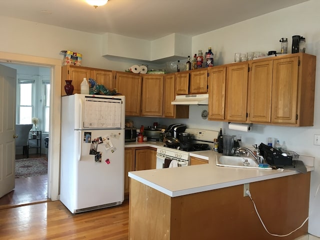 kitchen with white appliances, light hardwood / wood-style flooring, kitchen peninsula, and sink