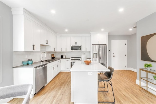 kitchen with appliances with stainless steel finishes, white cabinetry, a kitchen island, and sink