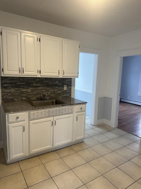 kitchen featuring baseboard heating, a sink, and white cabinets