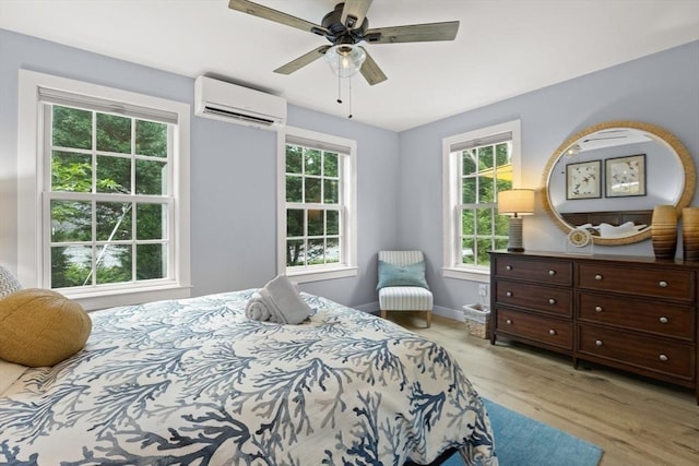 bedroom featuring ceiling fan, an AC wall unit, light hardwood / wood-style flooring, and multiple windows