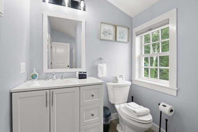 bathroom with toilet, vanity, and vaulted ceiling