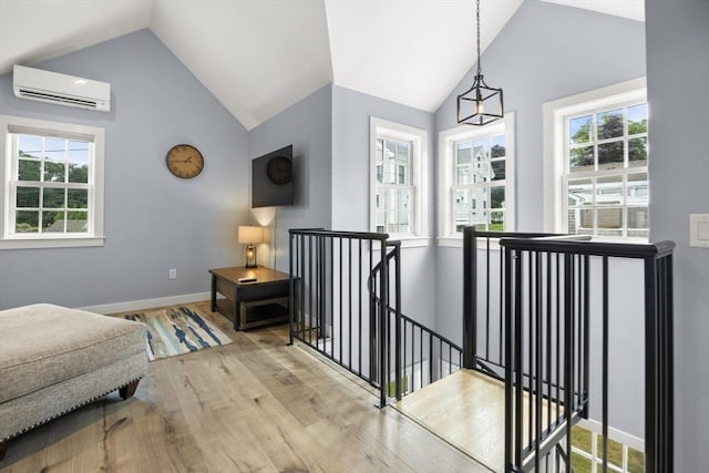 interior space with light wood-type flooring, vaulted ceiling, and a wall mounted AC