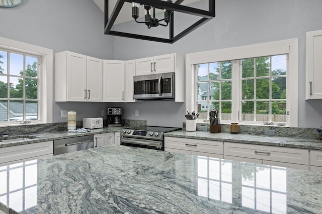 kitchen with stainless steel appliances, white cabinetry, a wealth of natural light, and sink