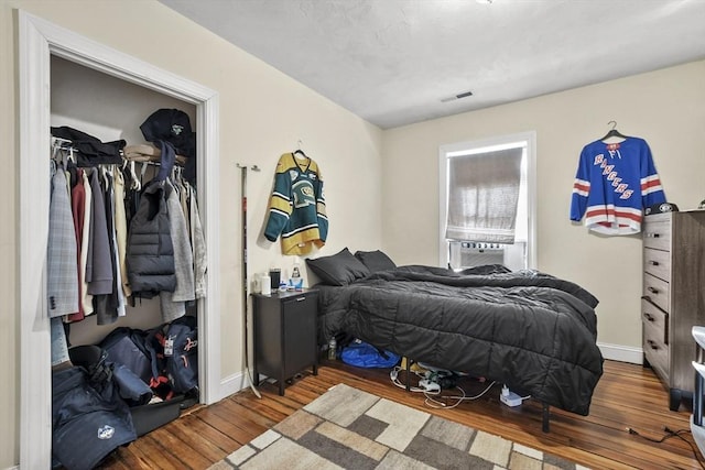 bedroom featuring baseboards, a closet, visible vents, and wood finished floors