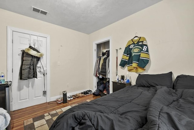 bedroom featuring wood finished floors, visible vents, and baseboards