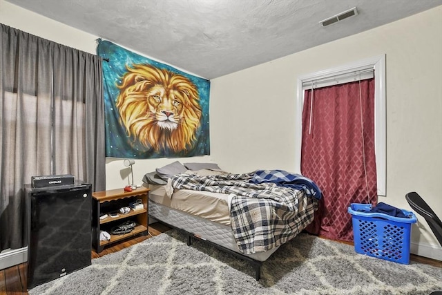 bedroom featuring wood finished floors and visible vents