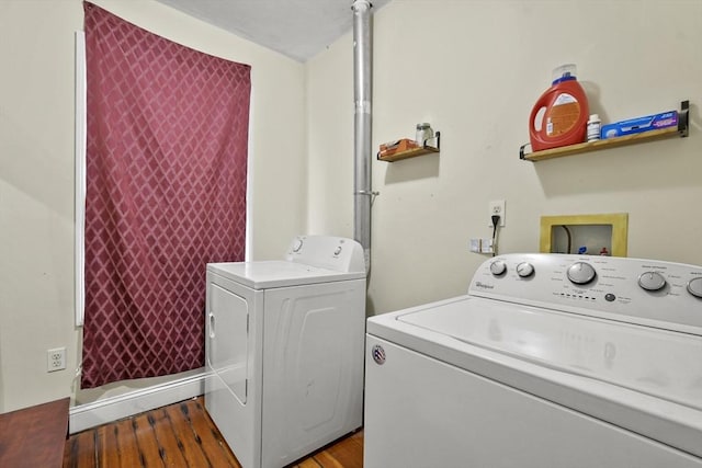 clothes washing area featuring laundry area, wood finished floors, and washing machine and clothes dryer