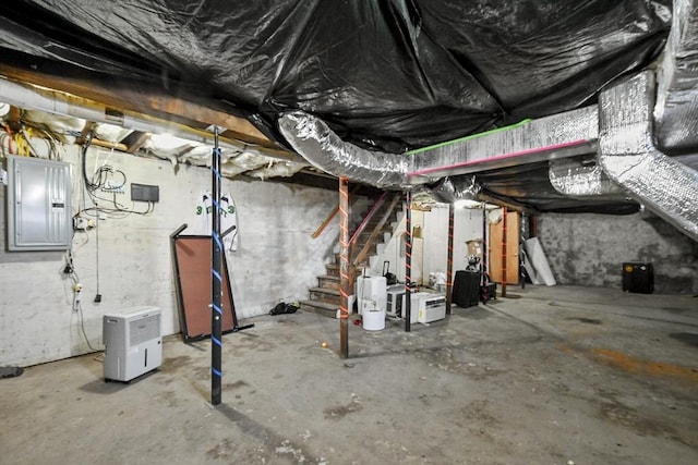 unfinished basement featuring electric panel and stairs