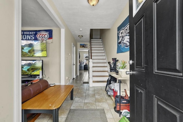 tiled foyer with baseboards and stairs