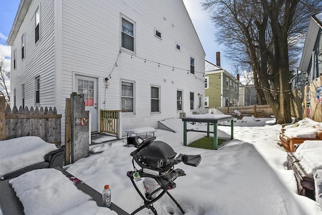 snow covered property with fence