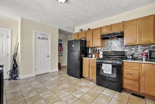 kitchen featuring light tile patterned floors, under cabinet range hood, baseboards, decorative backsplash, and black appliances