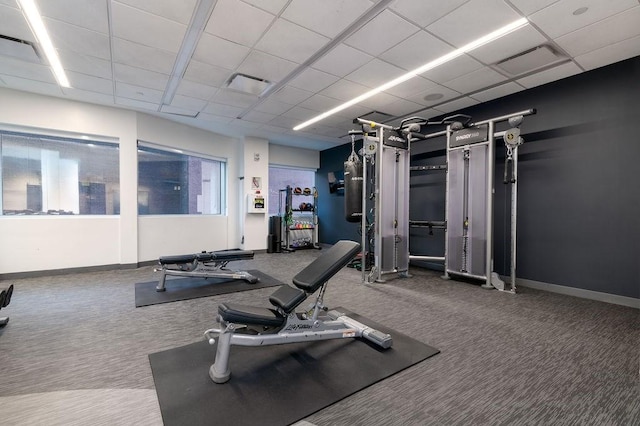 gym featuring carpet floors, baseboards, and a paneled ceiling