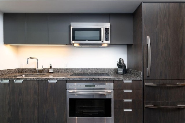 kitchen featuring stainless steel appliances, modern cabinets, a sink, and dark brown cabinetry