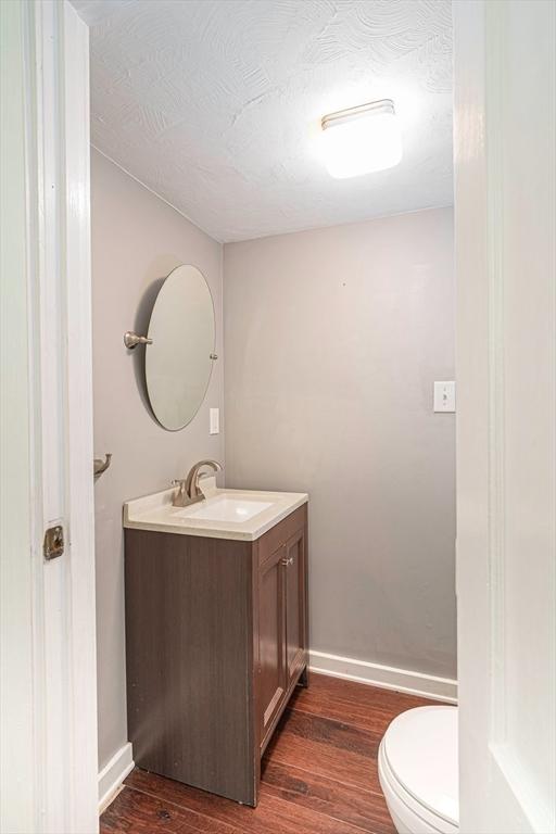 67 Pine St, Milford, MA 01757 - bathroom with vanity, wood finished floors, toilet, baseboards, and a textured ceiling