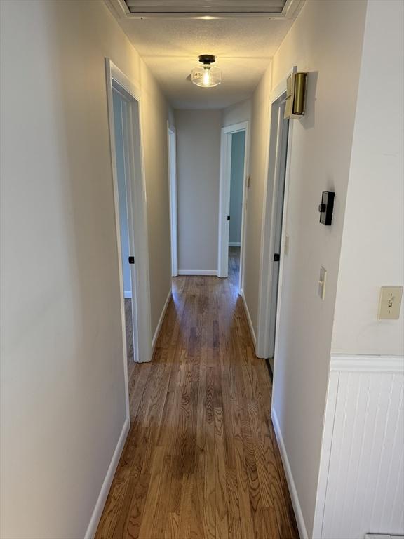 corridor with baseboards and wood finished floors