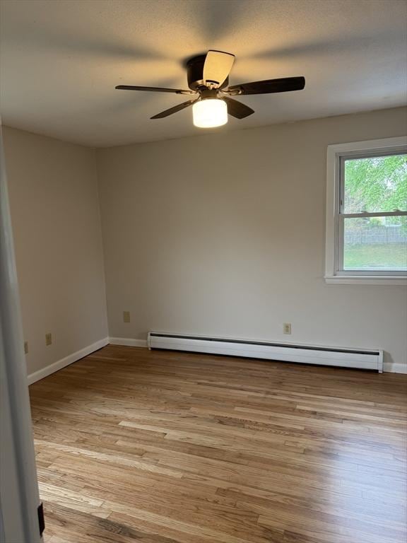 empty room with a ceiling fan, light wood-type flooring, baseboards, and baseboard heating