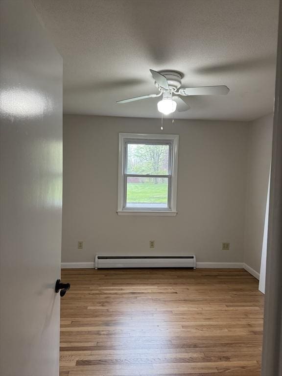 spare room featuring baseboards, baseboard heating, ceiling fan, and wood finished floors