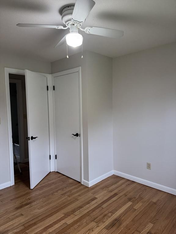 empty room with baseboards, a ceiling fan, and wood finished floors
