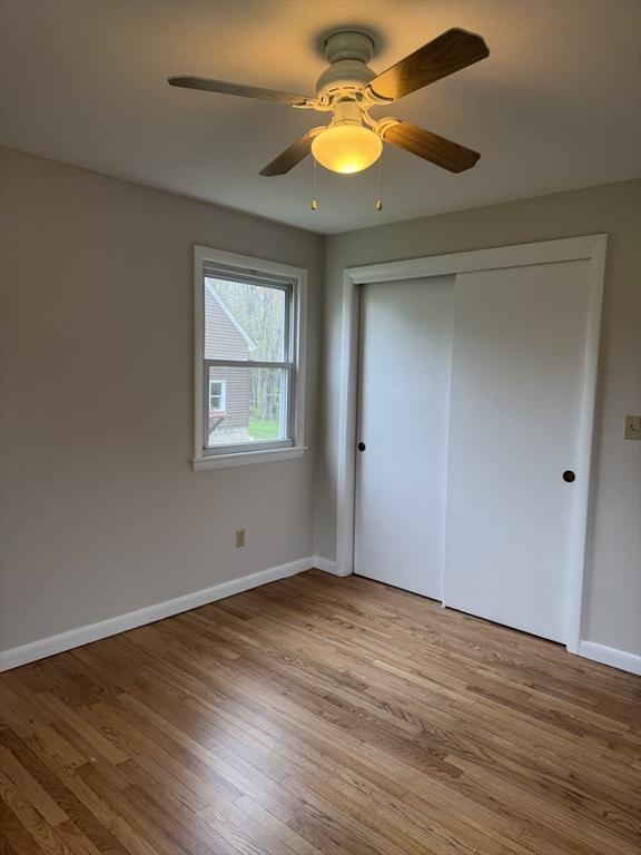 unfurnished bedroom featuring baseboards, a closet, light wood-type flooring, and a ceiling fan