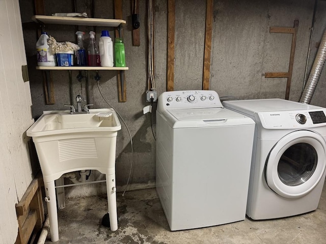 washroom featuring washing machine and dryer, laundry area, and a sink