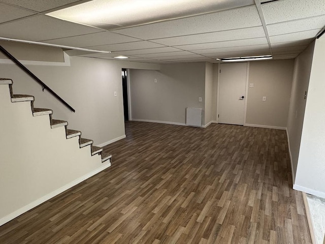 finished basement featuring a drop ceiling, wood finished floors, baseboards, and stairs