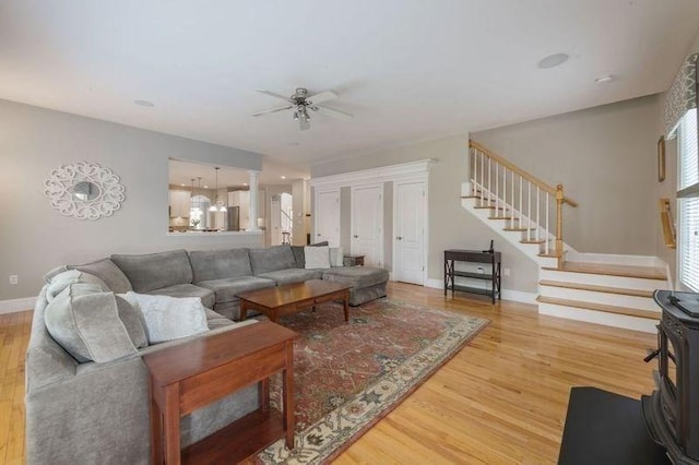 living area with stairs, baseboards, a ceiling fan, and wood finished floors