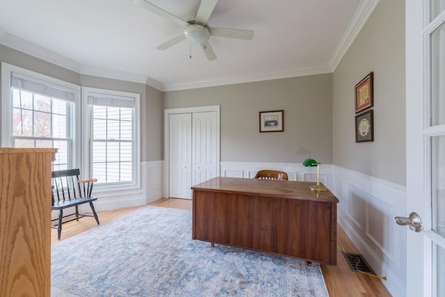 home office with wood finished floors, ceiling fan, visible vents, and a wainscoted wall